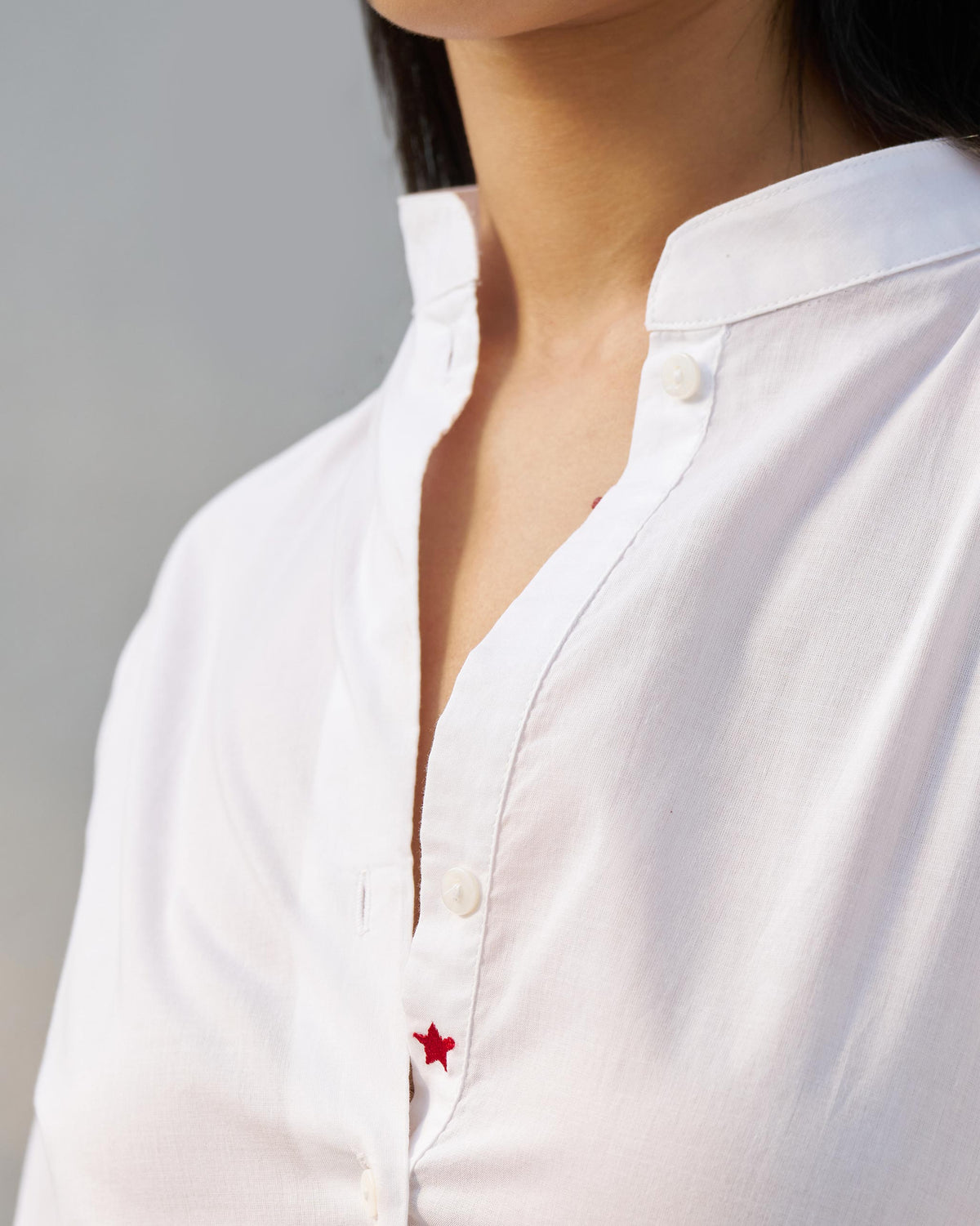 Close-up of a white Moon set collar with a red star on the placket.