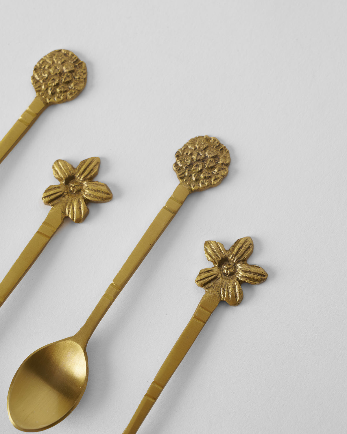 Close-up of gold Bloom Coffee Spoons showing flower and textured blossom tops.