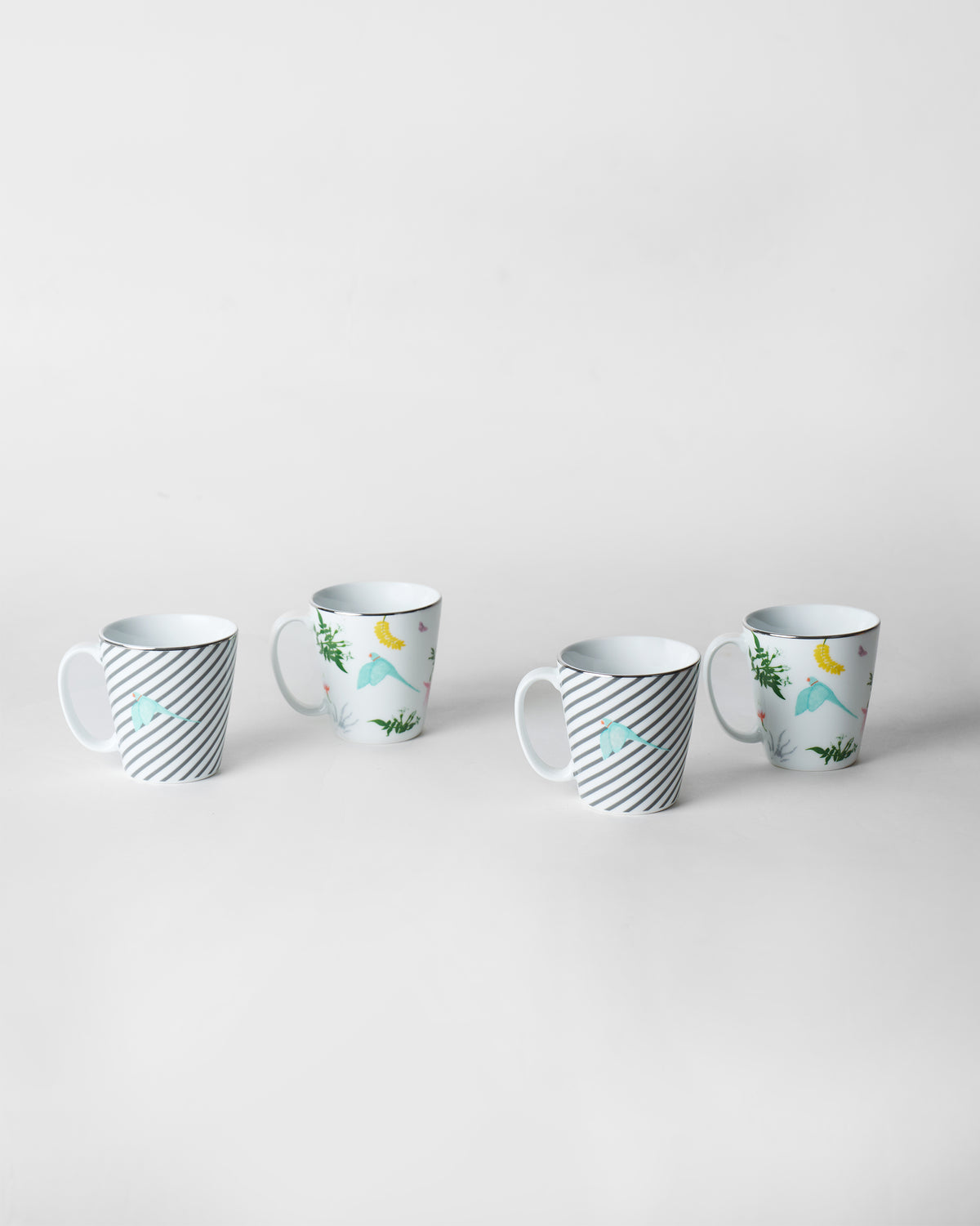 Four Botanical Coffee Mugs alternating stripe and tropical bird prints.