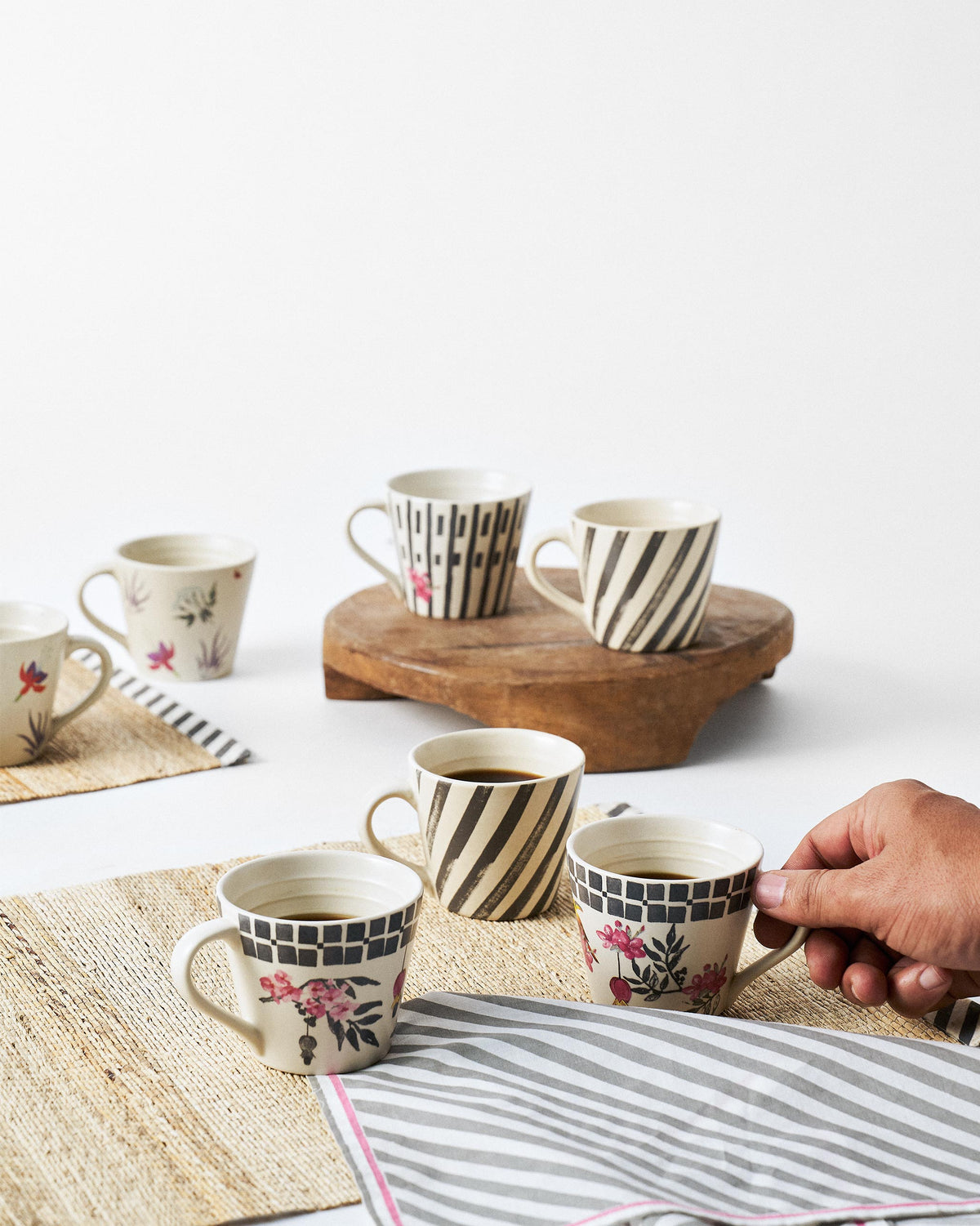 Hand holding a Tropic Espresso Mug with a pink floral print and checked band.