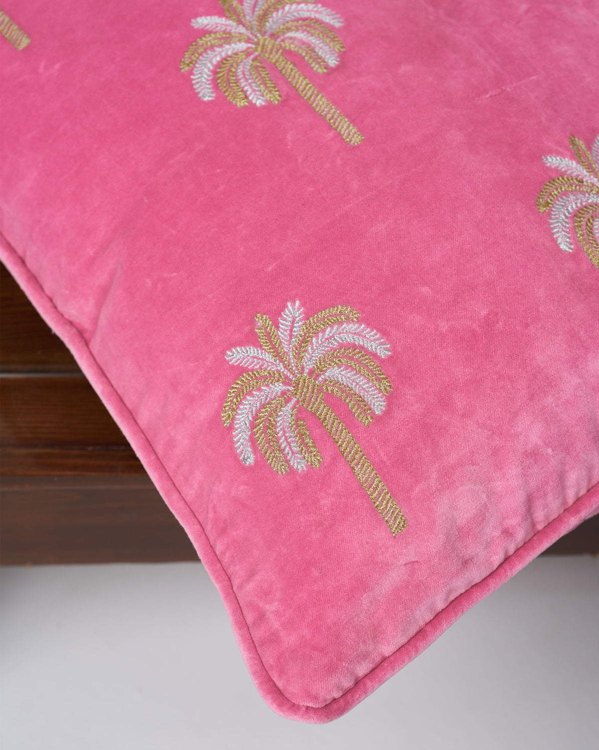 Close-up of pink Palm Shimmer cushion cover showing embroidered palm trees.