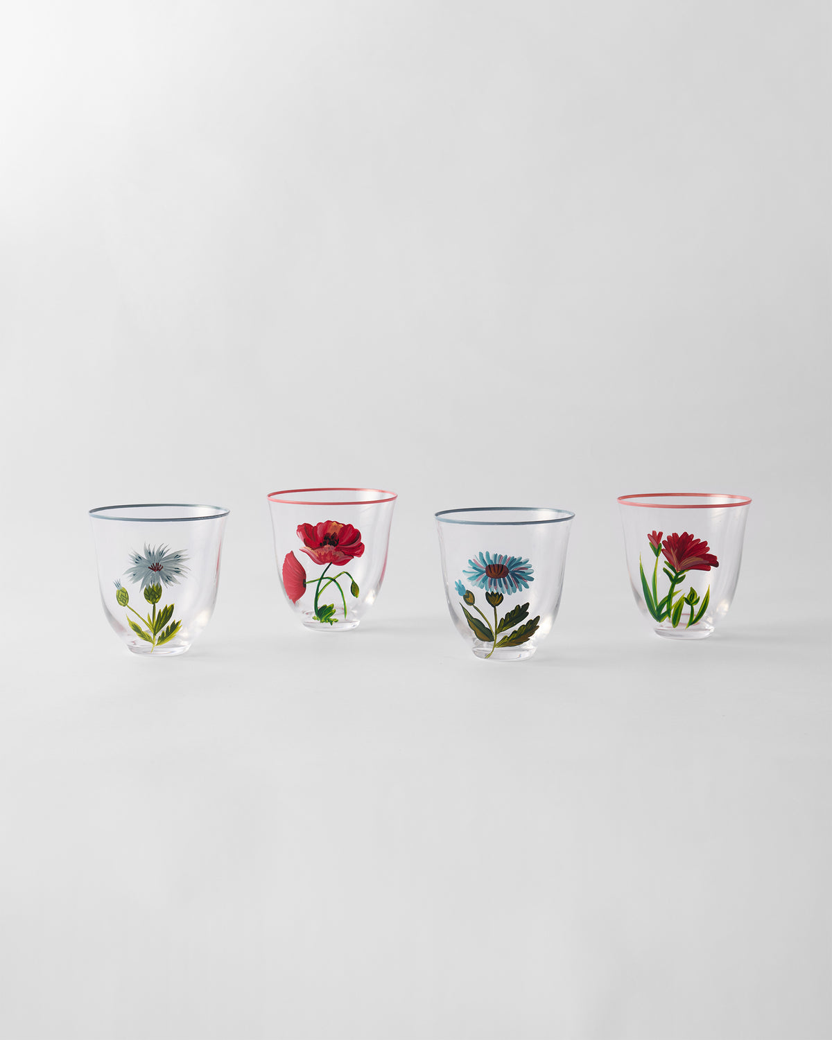 Four clear Rit tumblers lined up, each with a different flower and colored rim.