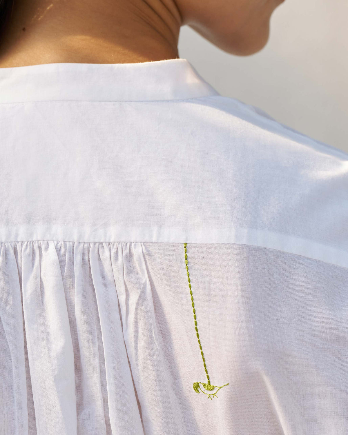 Close-up of gathered back yoke with a green bird on a white top.
