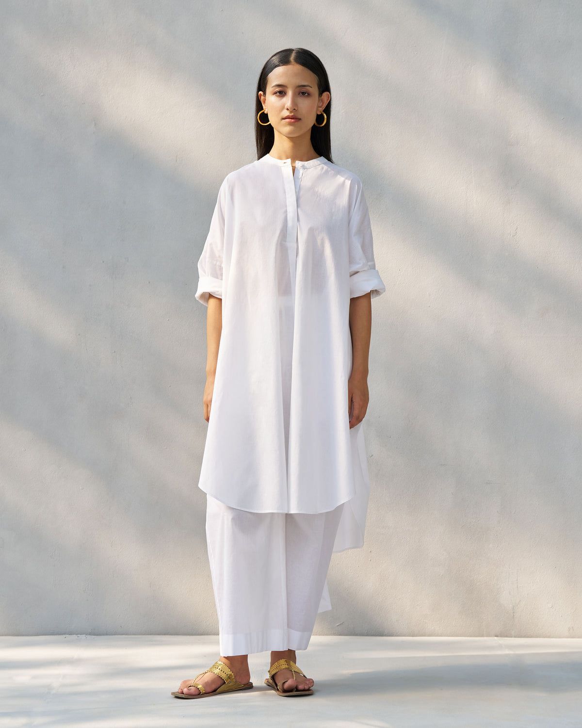 Person wearing the Alba set in white, a long band-collar tunic.
