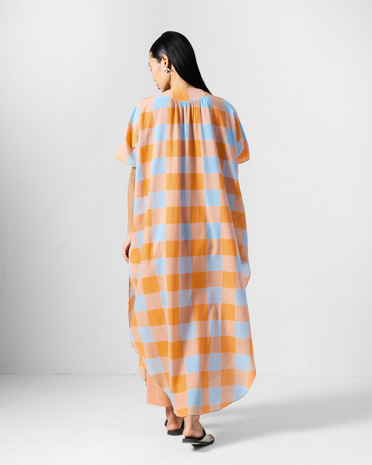 Back of an orange and blue check Vaya kaftan with a gathered yoke.