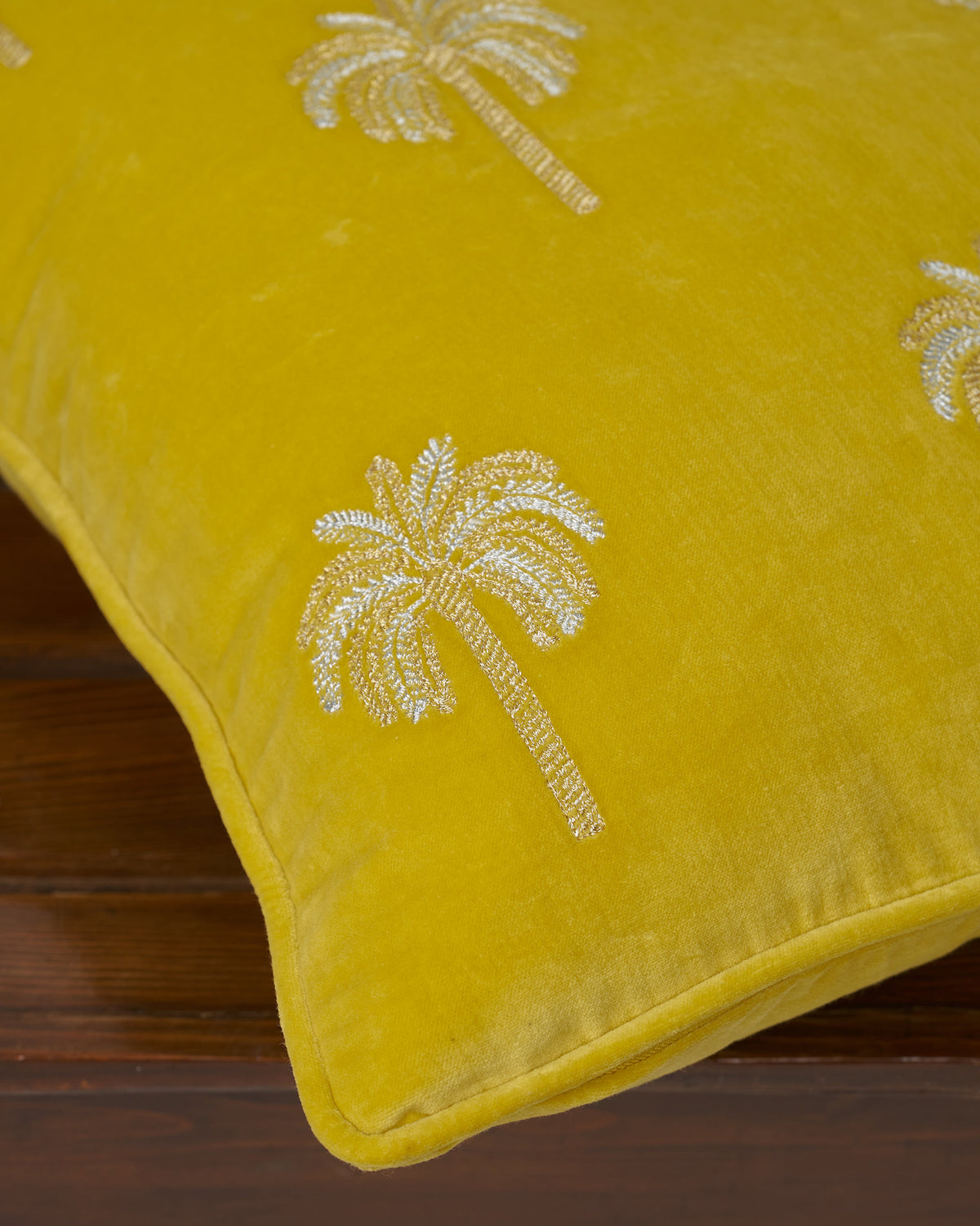 Close-up of yellow Palm Shimmer cushion cover showing silver embroidered palms.