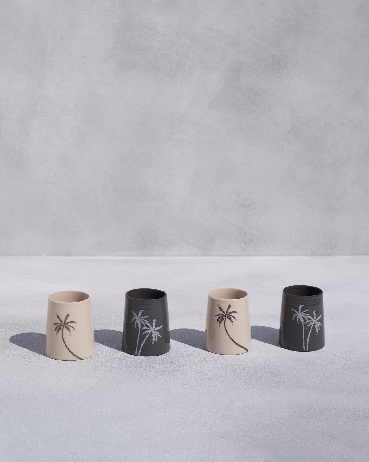 Four Swaying Palm kulhars in cream and charcoal with palm tree motifs.