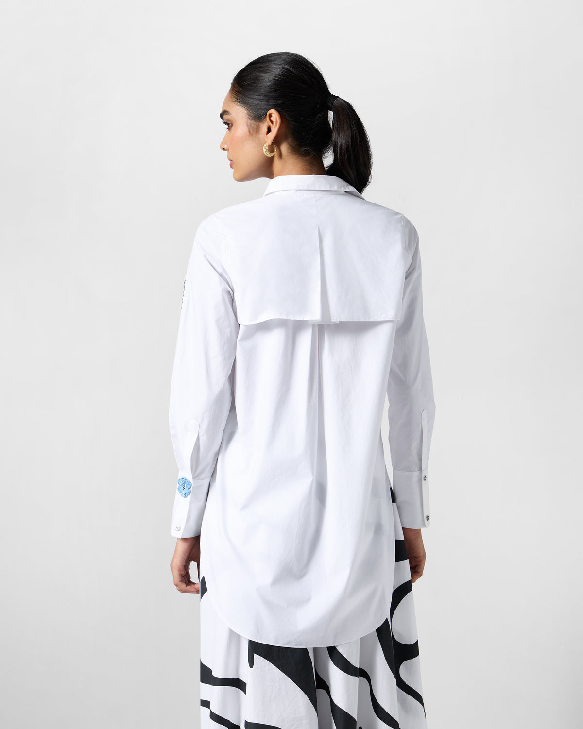 Back of a white trench shirt with a yoke flap and center box pleat.