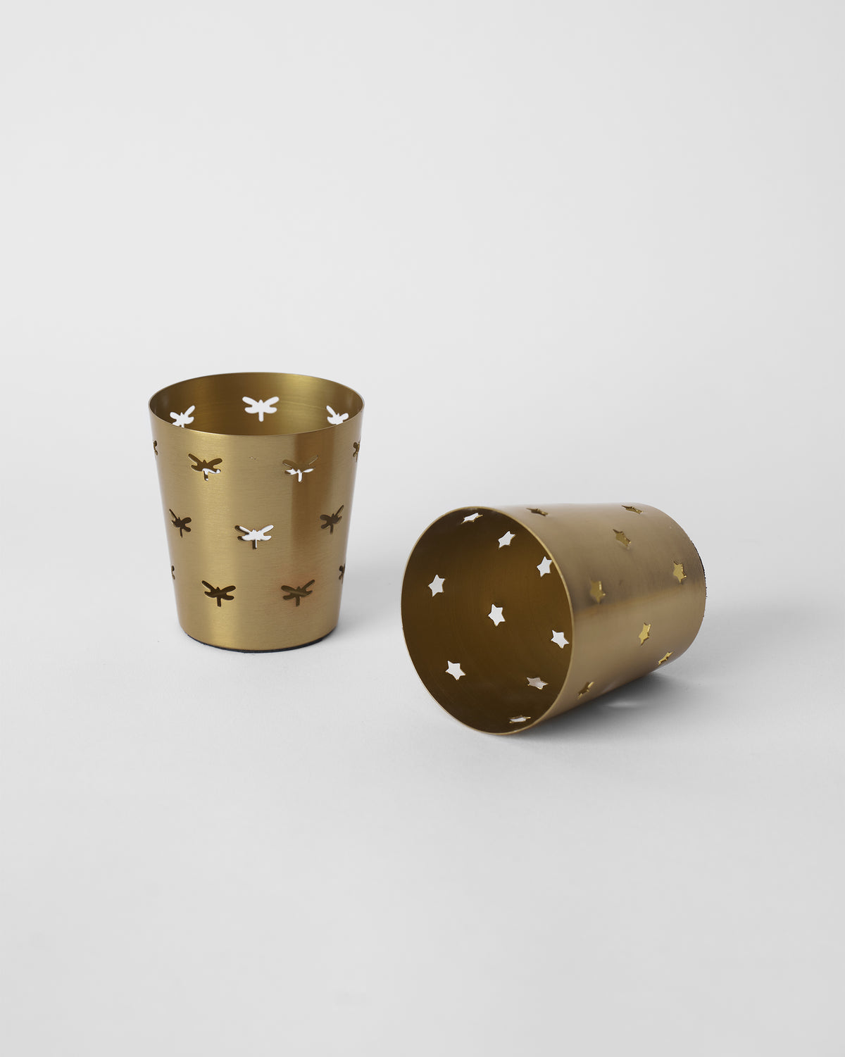 Smriti gold votives with one upright and one tipped to show the interior.