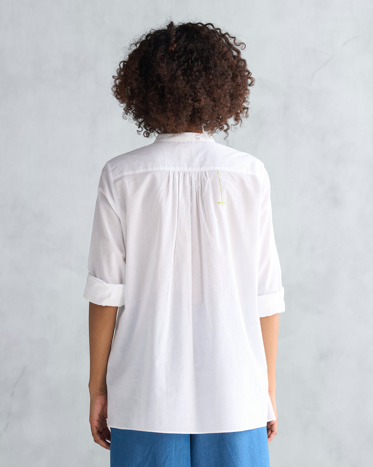 Back of a white mandarin collar top with a gathered yoke.