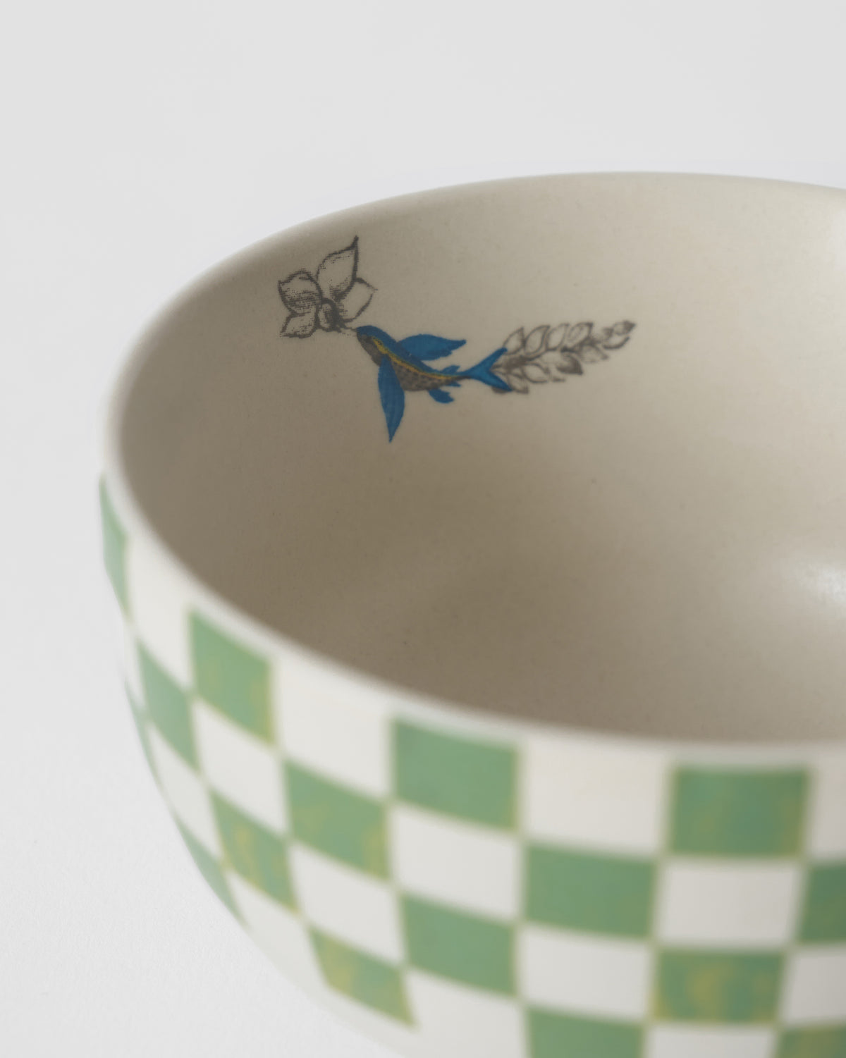Close-up of a Reesha katori showing green checks and a blue bird on the rim.