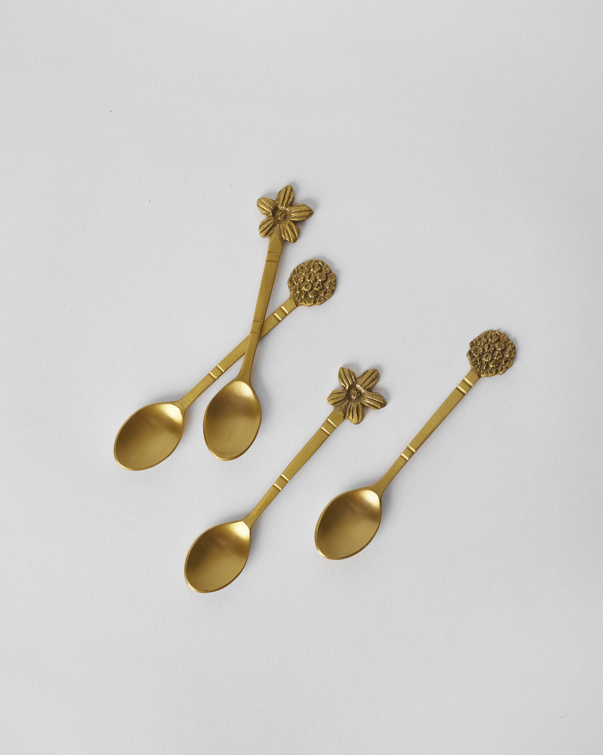 Four gold Bloom Coffee Spoons arranged to show flower and blossom finials.
