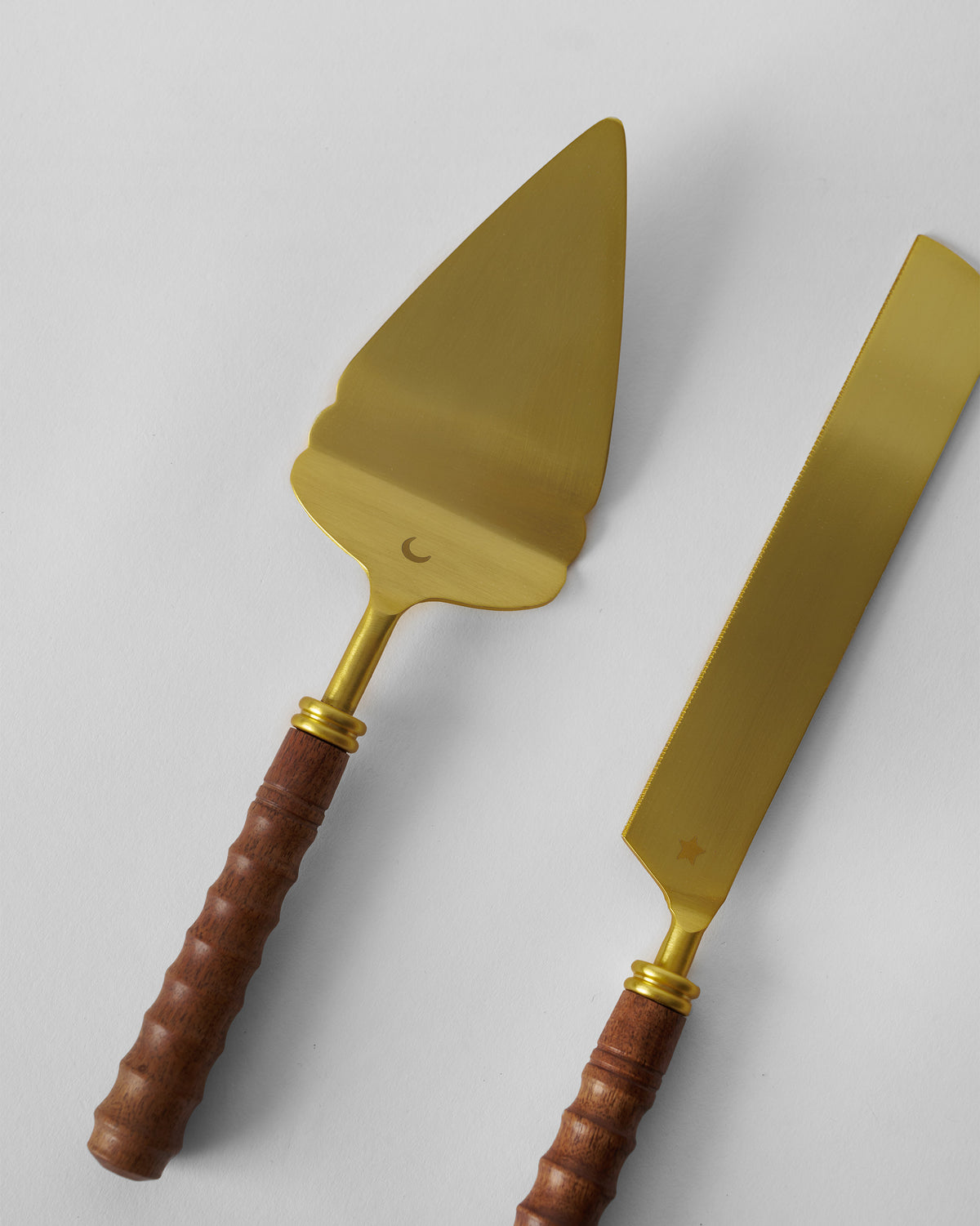 Close-up of gold cake knife and server showing moon and star engravings.