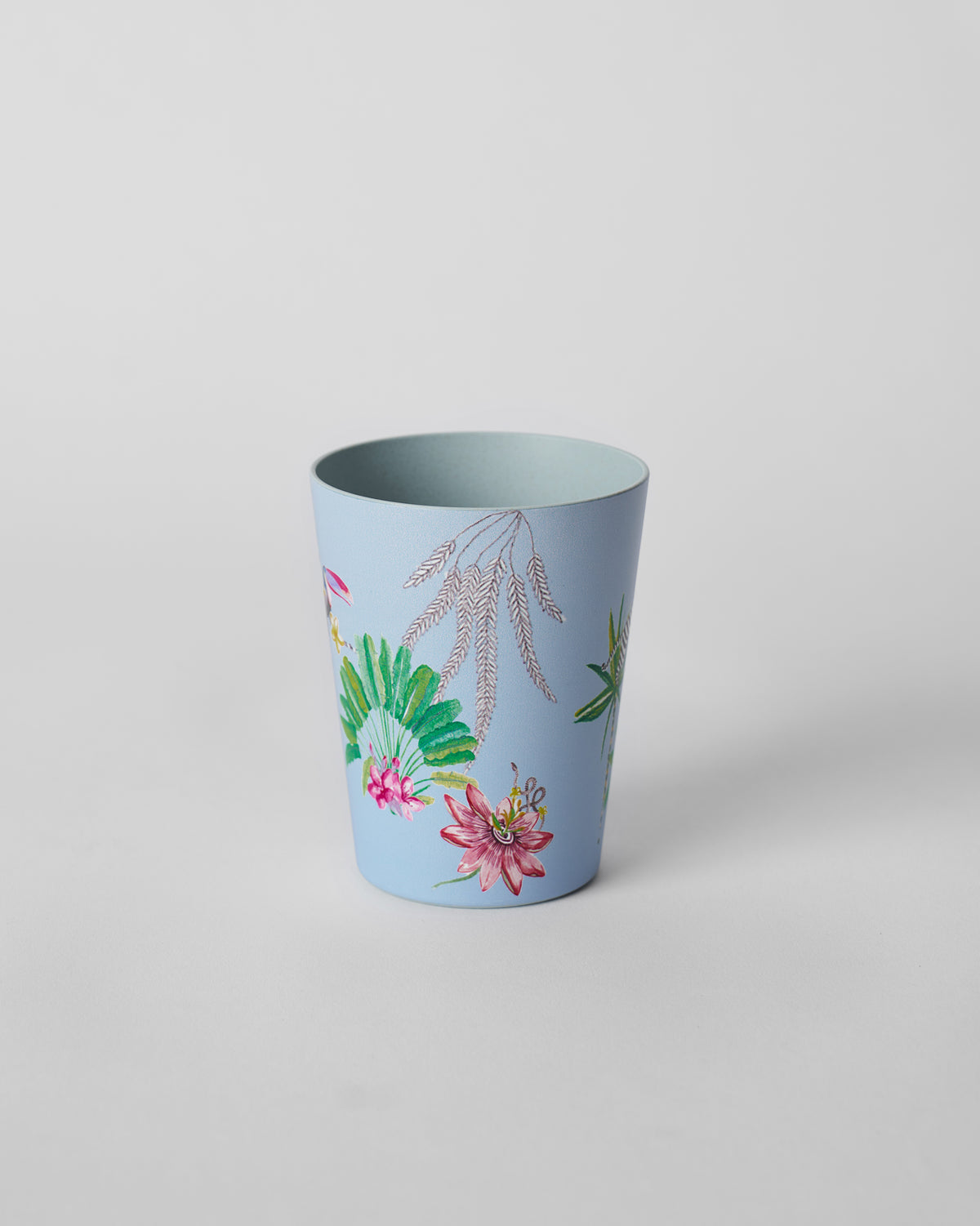 Dusty blue Toucan bamboo tumbler showing pink blossoms and green leaves near the base.