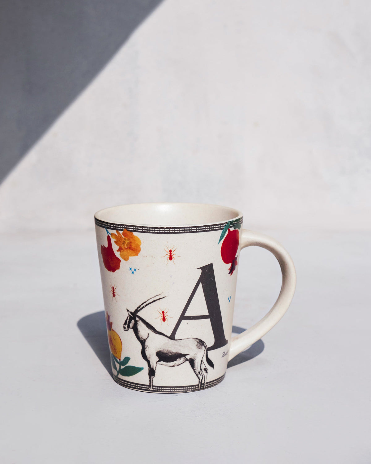 Cream alphabet mug with the letter A and animal motifs.