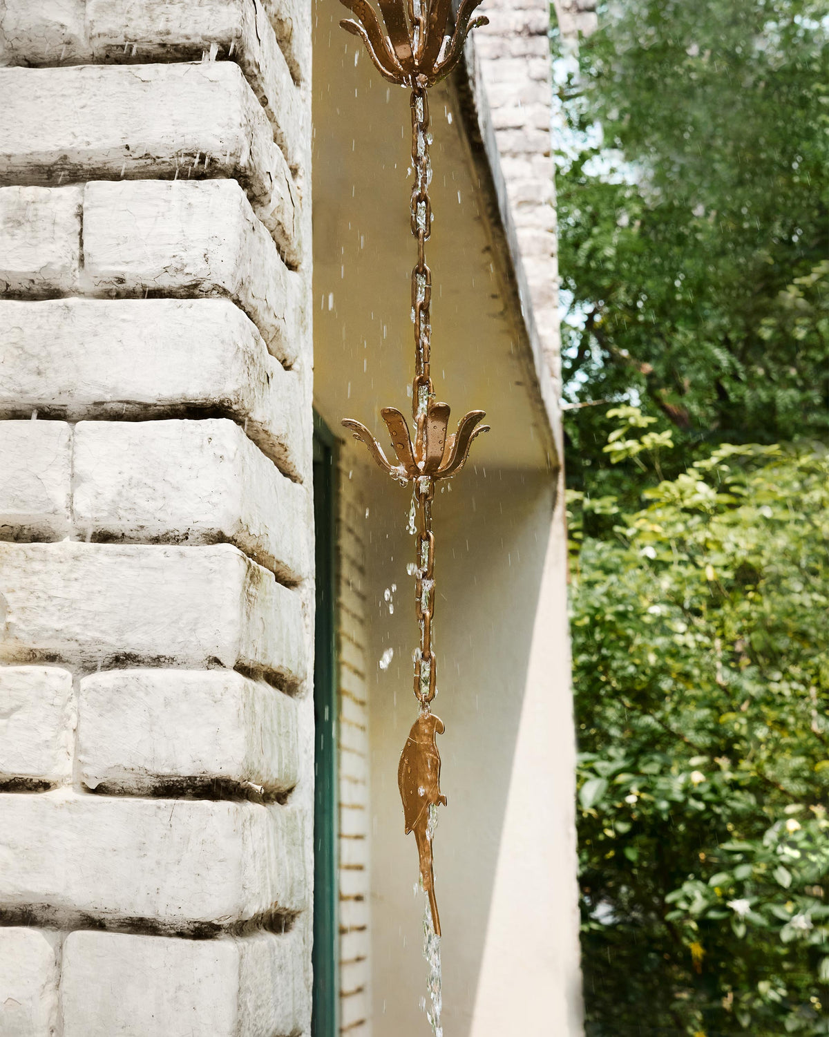 Madagascar Rain Chain hanging from a roof edge with a parrot pendant at the bottom.