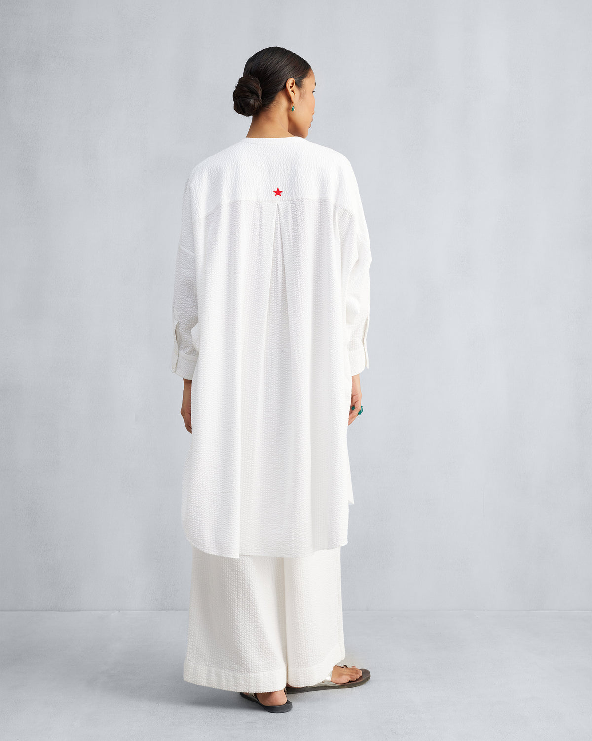 Back of a white Lazy Sunday tunic with a red star and box pleat.
