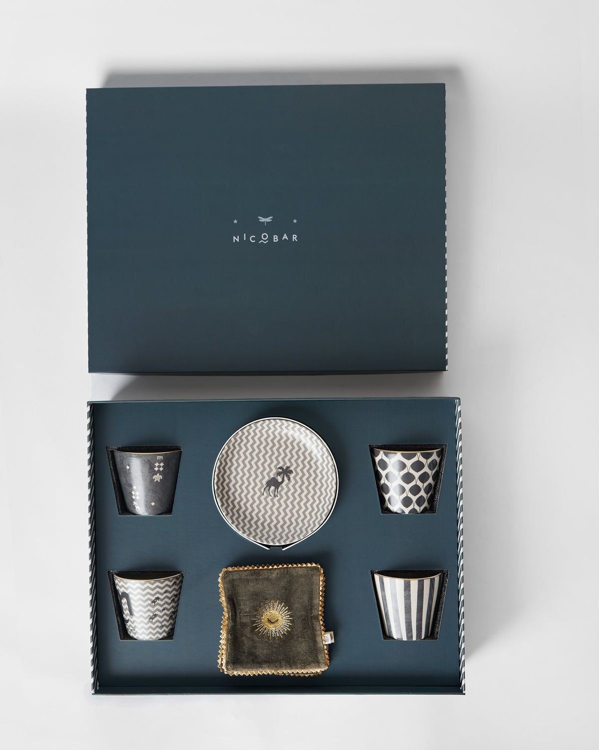 Open Twilight gift box holding patterned cups, a plate and an olive coaster.