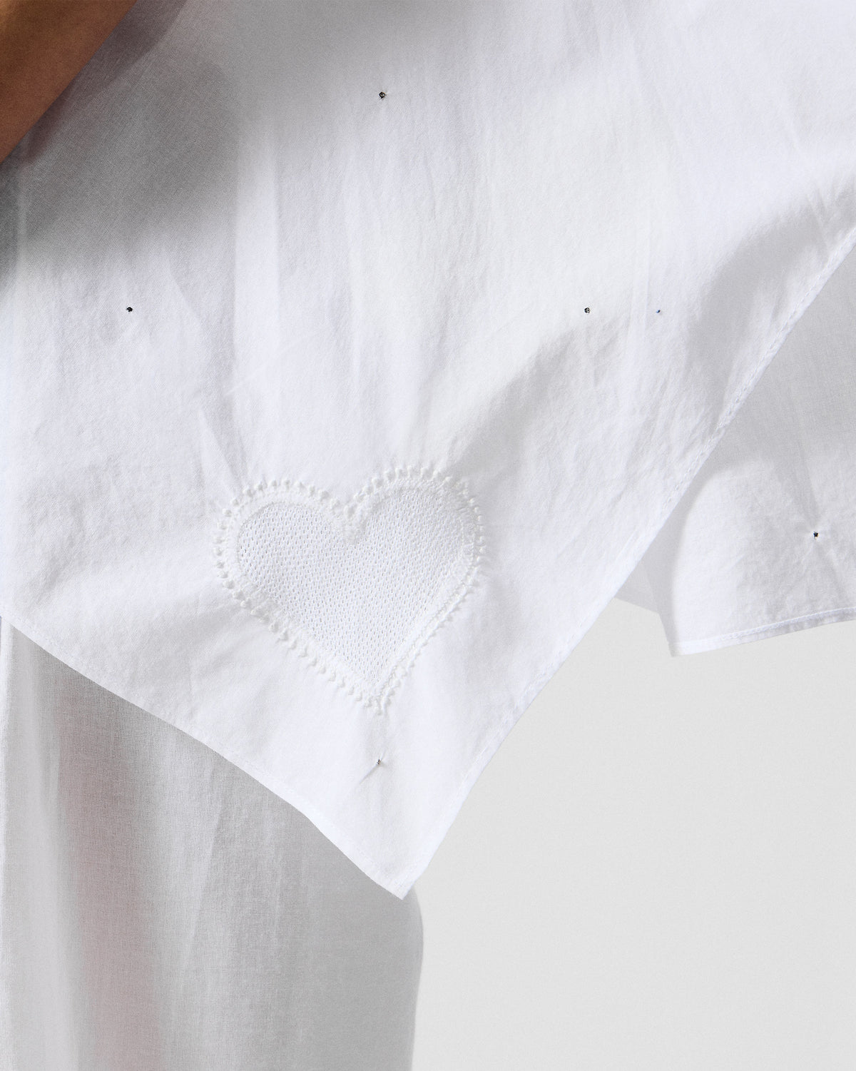 Close-up of a white embroidered heart on an ivory Riva top.