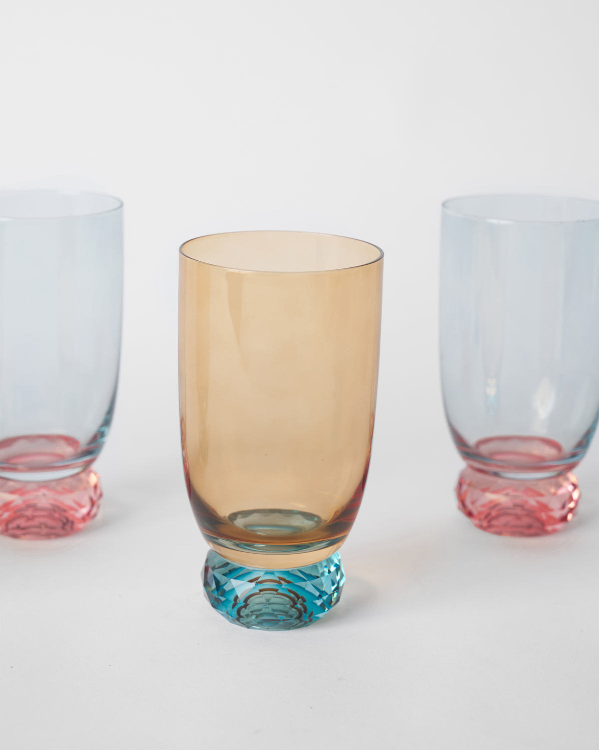 Reva sharbat glass with an amber bowl and a teal faceted base.