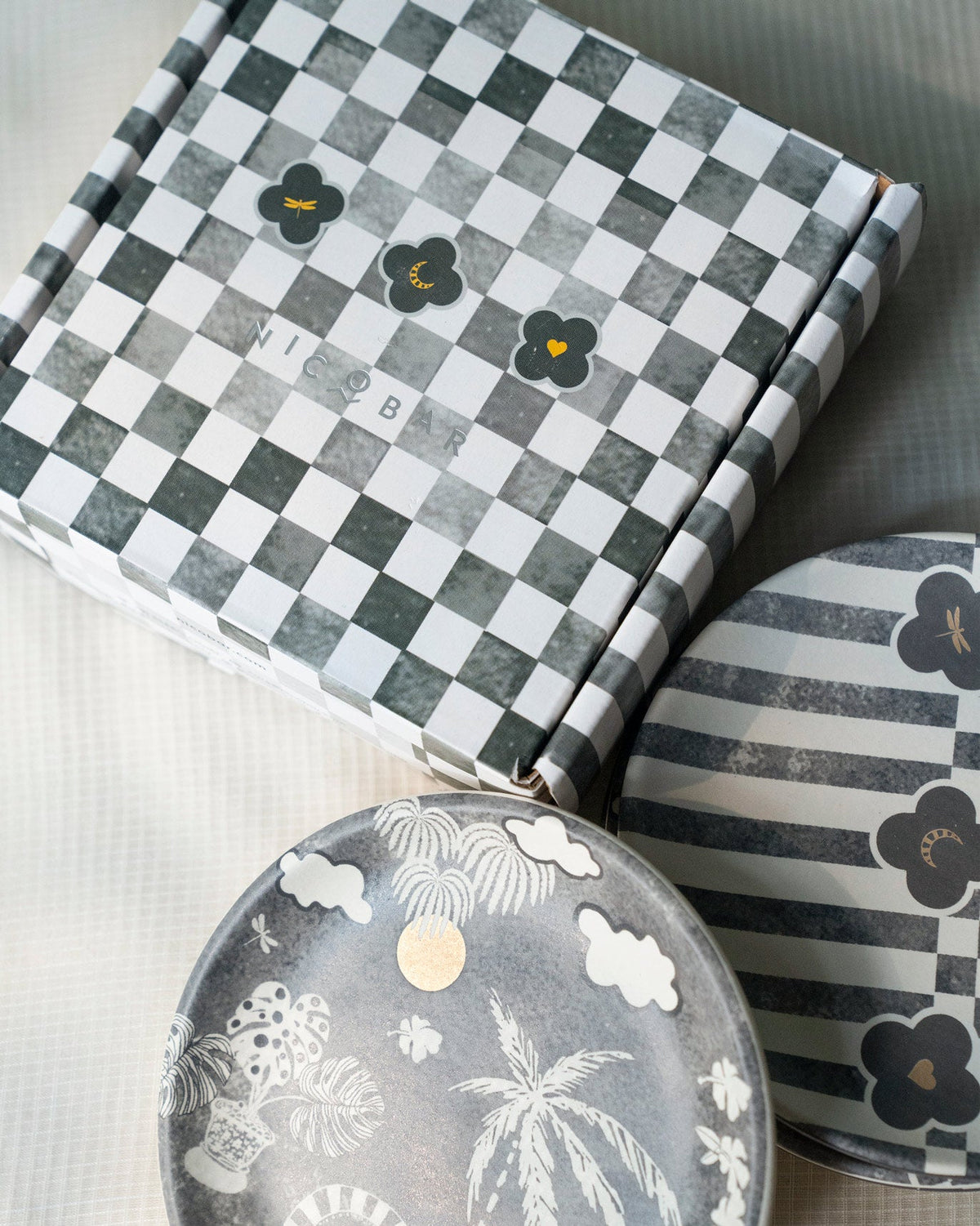 Mandovi tea plates beside a checkered Nicobar gift box.