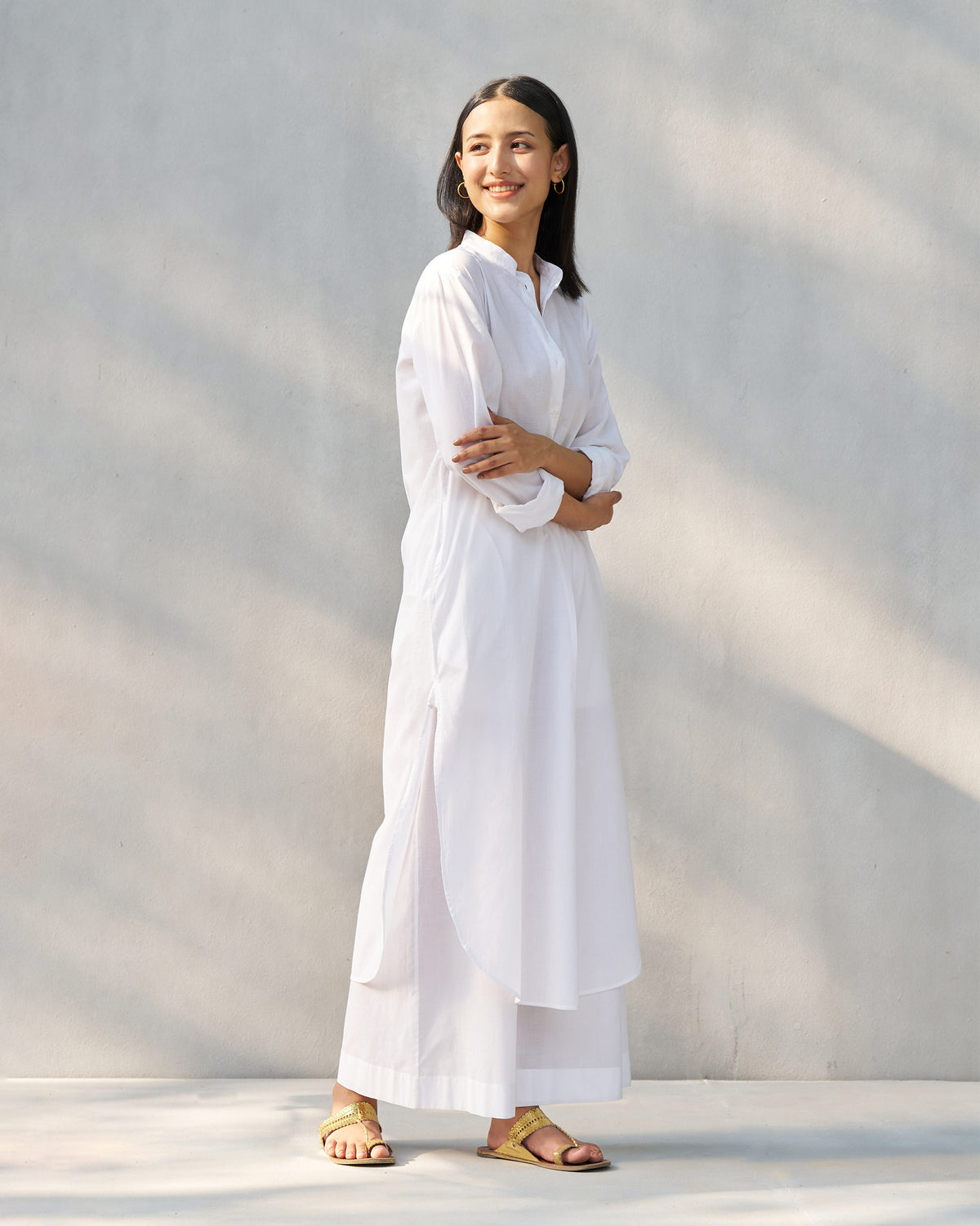 White long kurta set with high side slits and matching wide-leg pants.