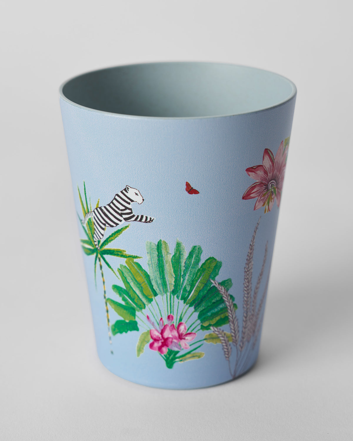Dusty blue Toucan bamboo tumbler with a white tiger leaping among green palm leaves.