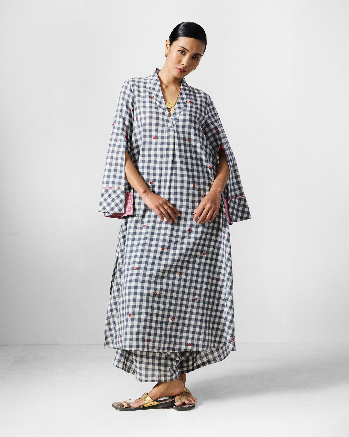 Person wearing a long grey and white check kurta set with pink sleeve lining.
