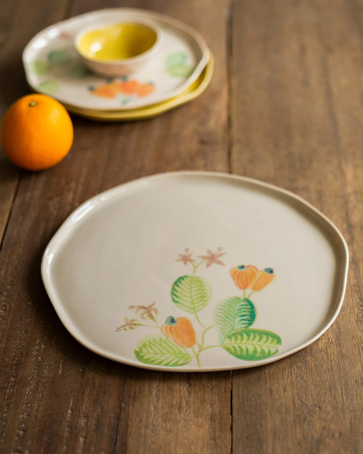 Close-up of a Mandovi dinner plate with cashew fruit and leaf motifs.