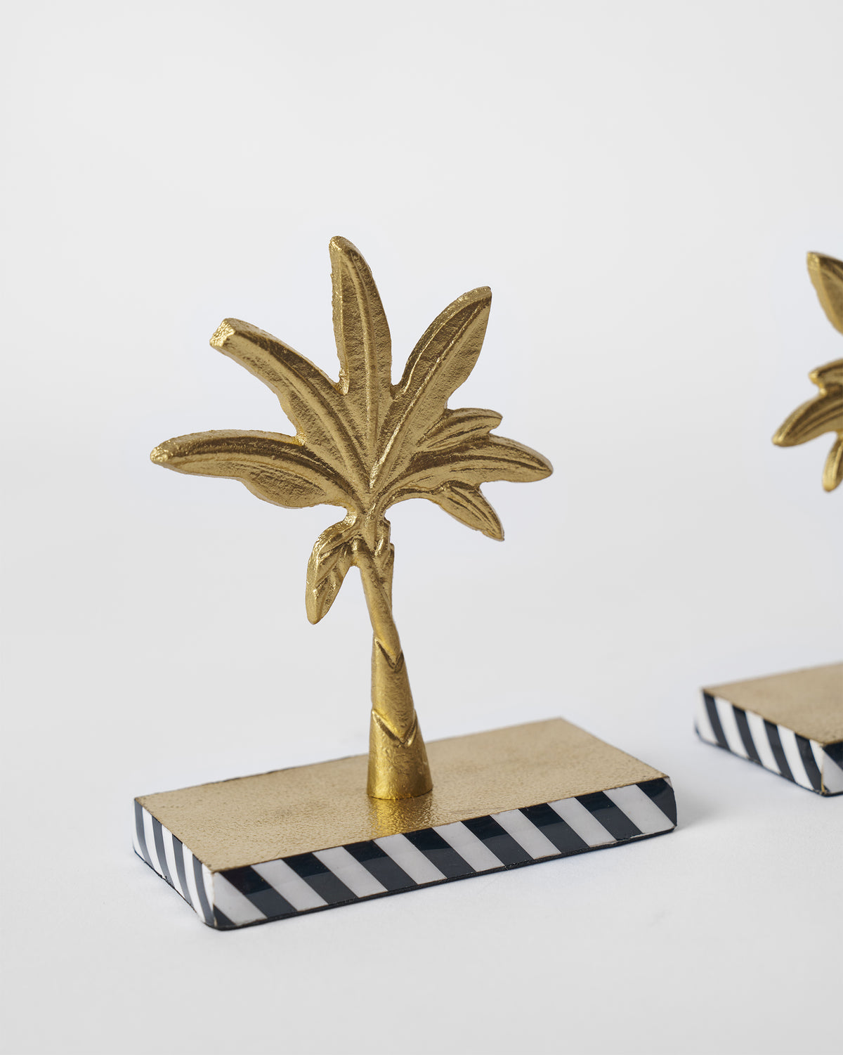 Close view of a Gilded Palm bookend with a gold palm on a striped base.