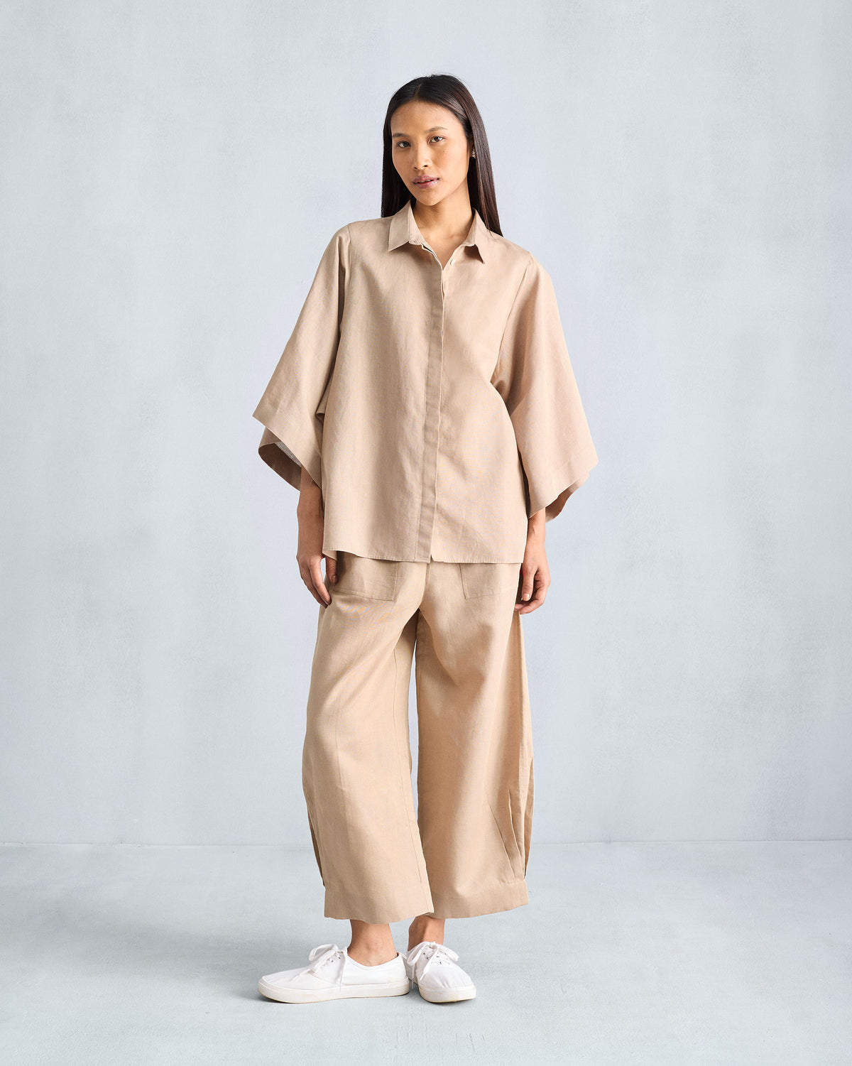 Person wearing a beige Drop Armhole shirt set with wide sleeves and matching trousers.