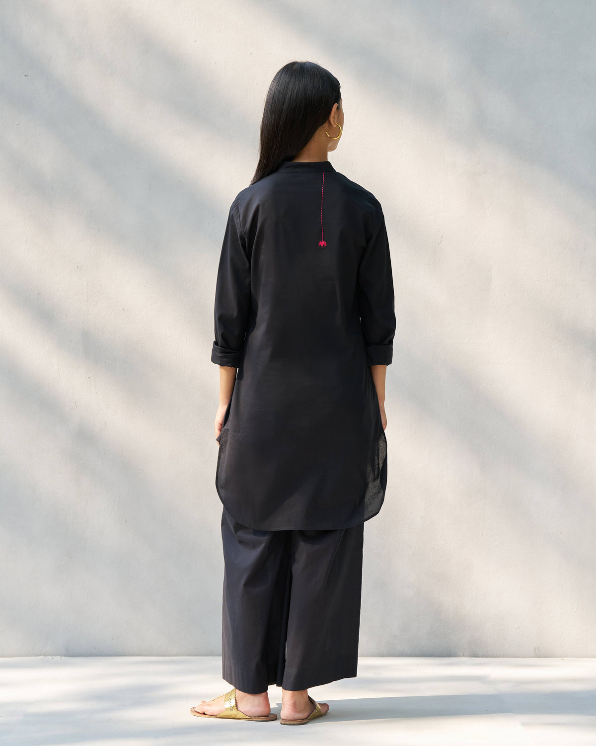 Back of a black Stone set tunic with a pink elephant embroidery.
