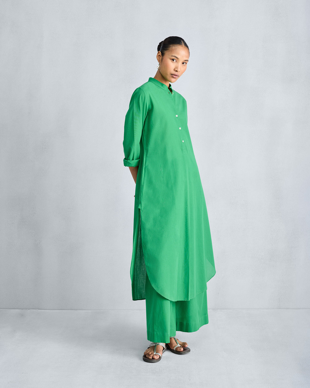 Three-quarter view of a green long kurta set with a curved hem.