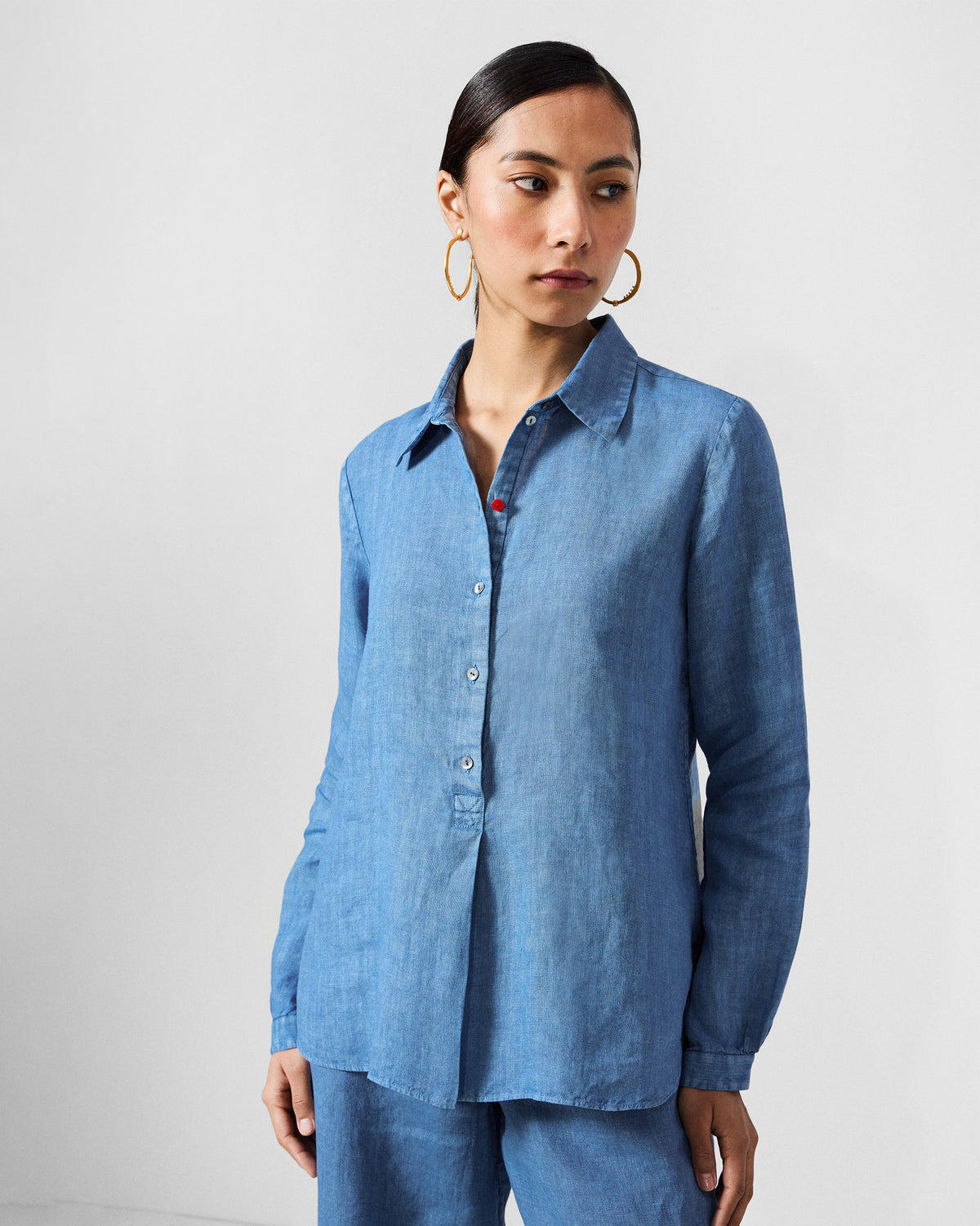 Person wearing a blue Mati shirt with a red button accent.