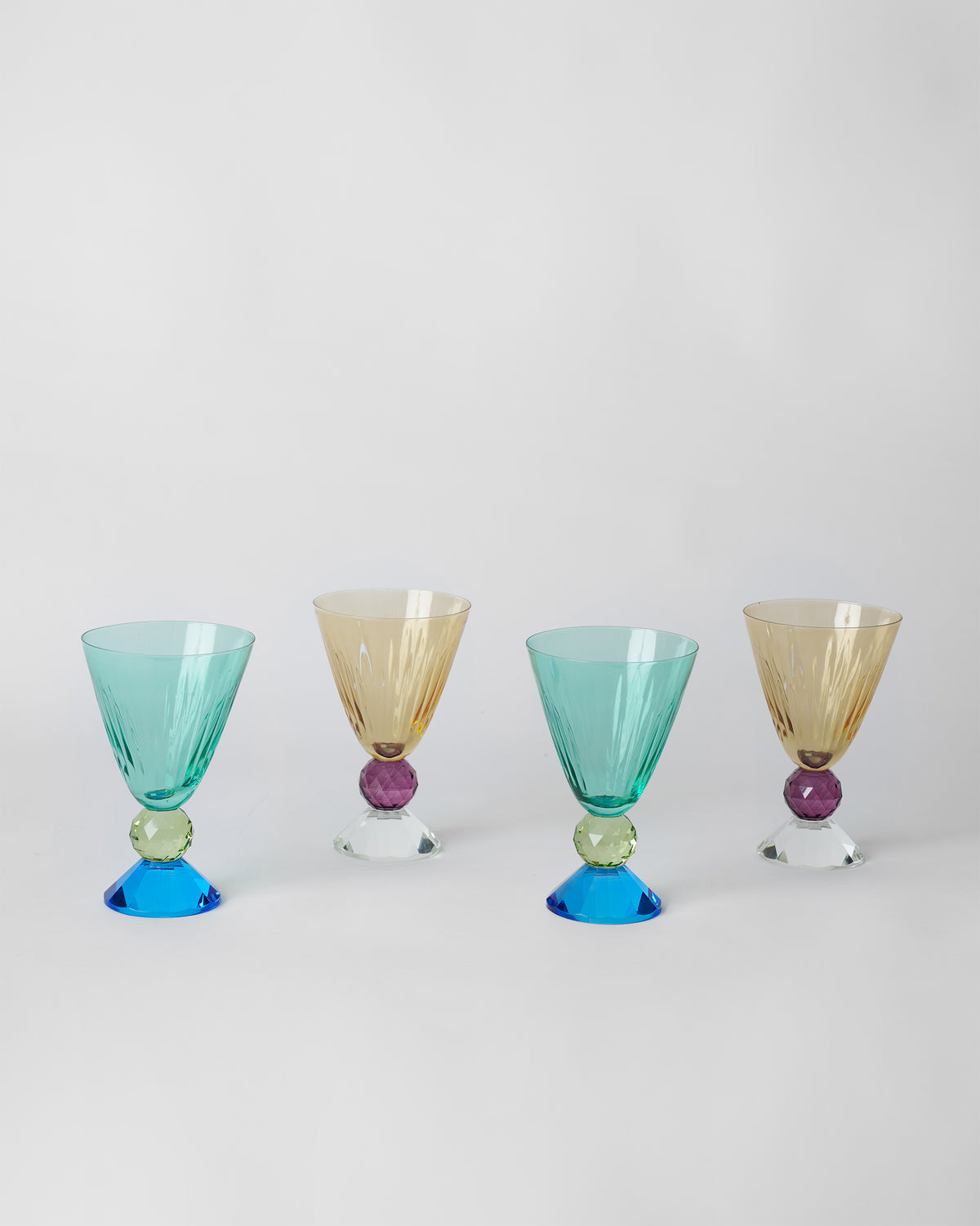 Four Vira cocktail glasses alternating teal and amber fluted bowls.