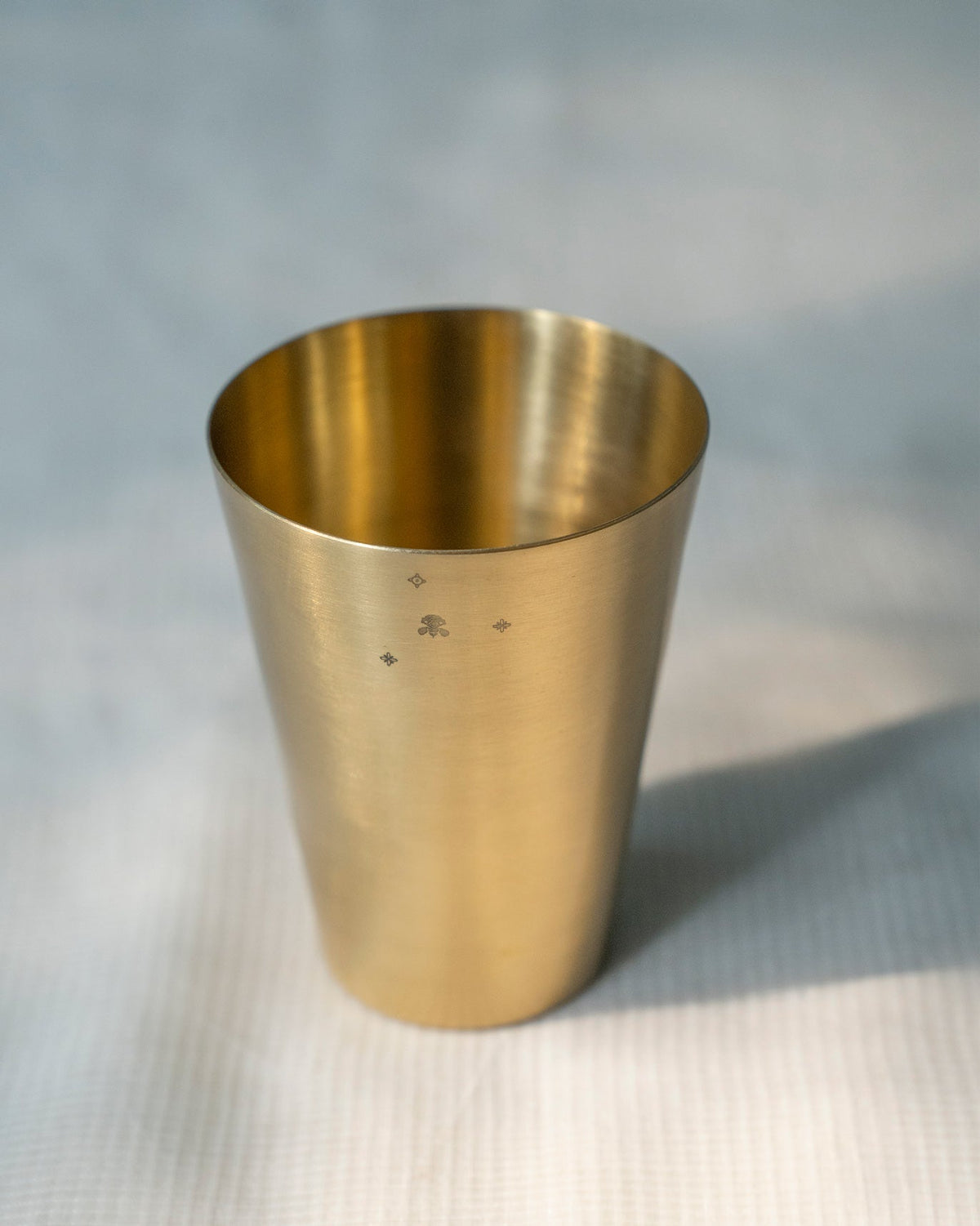 Brushed brass Madhu glass with a small palm and star motif.
