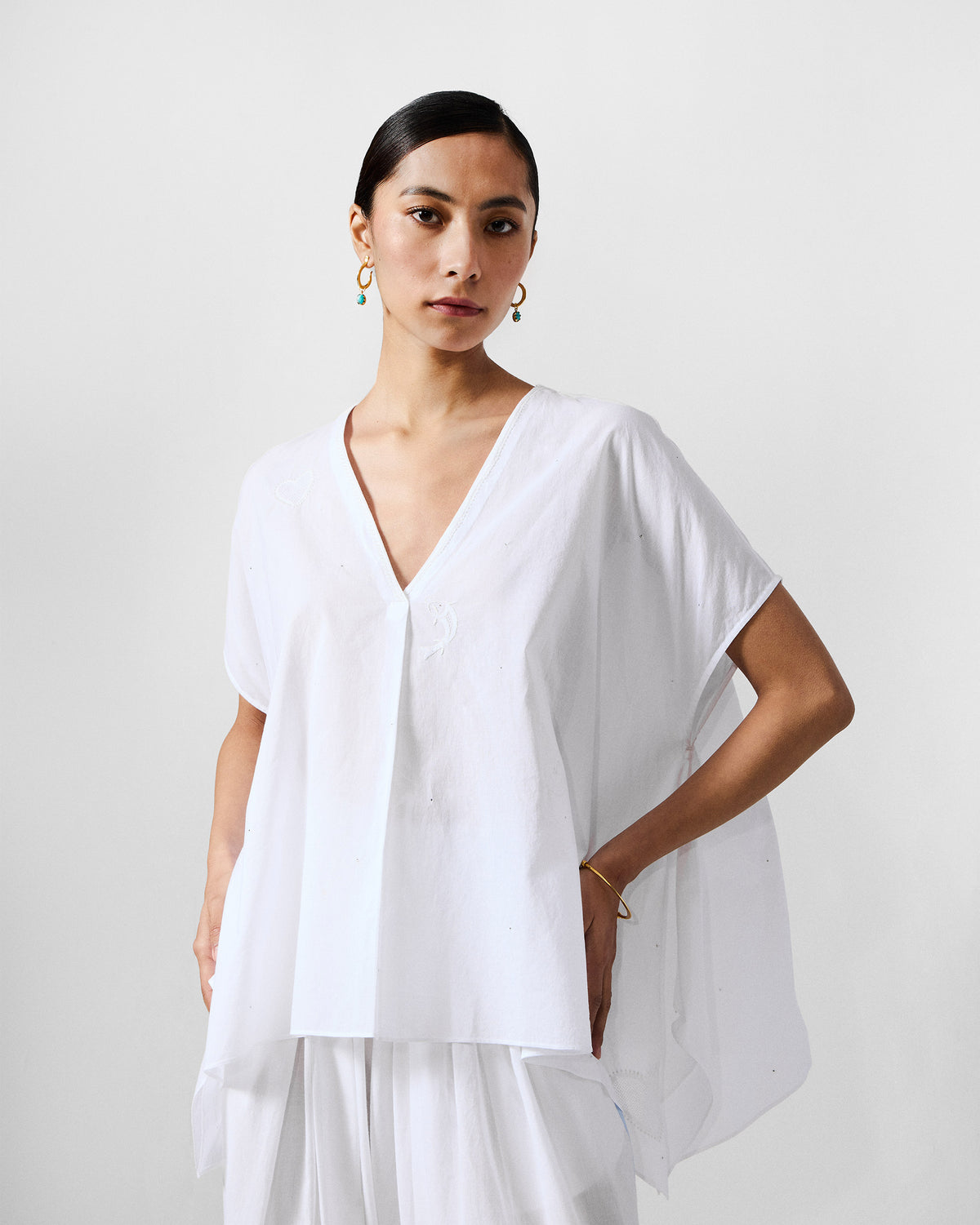 Person wearing an ivory Riva top with a deep V-neck and wide sleeves.