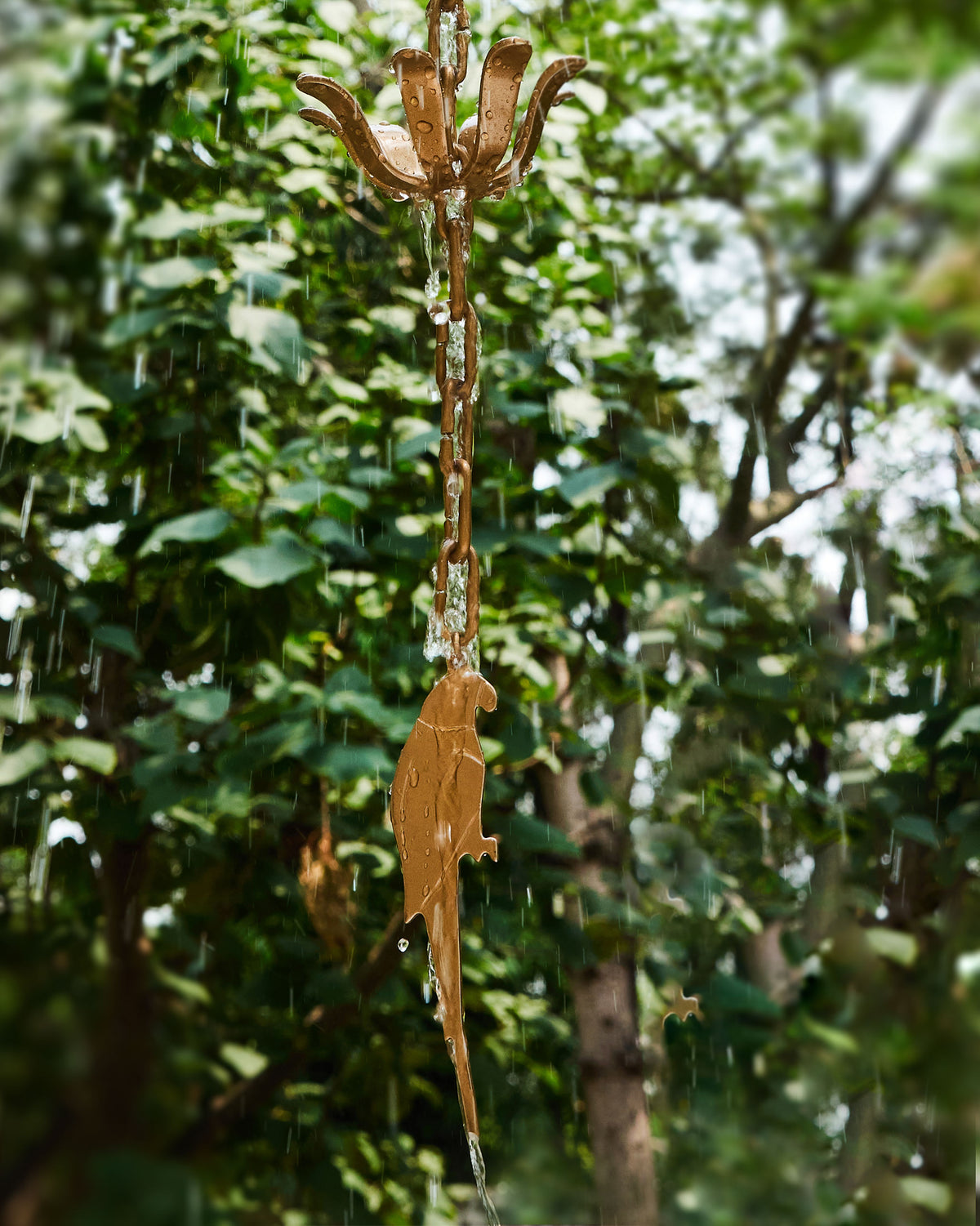 Madagascar Rain Chain hanging outdoors with a parrot pendant at the bottom.