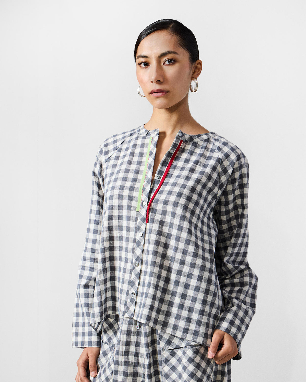 Person wearing a charcoal check Zil top with lime and red placket trim.