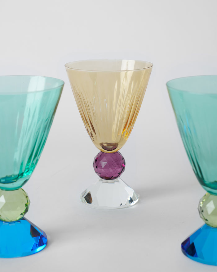 Close view of an amber glass on an amethyst crystal ball and a clear faceted foot