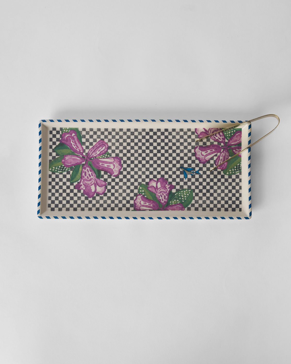 Overhead view of a Buransh Cookie Tray with purple blooms and gold tongs.