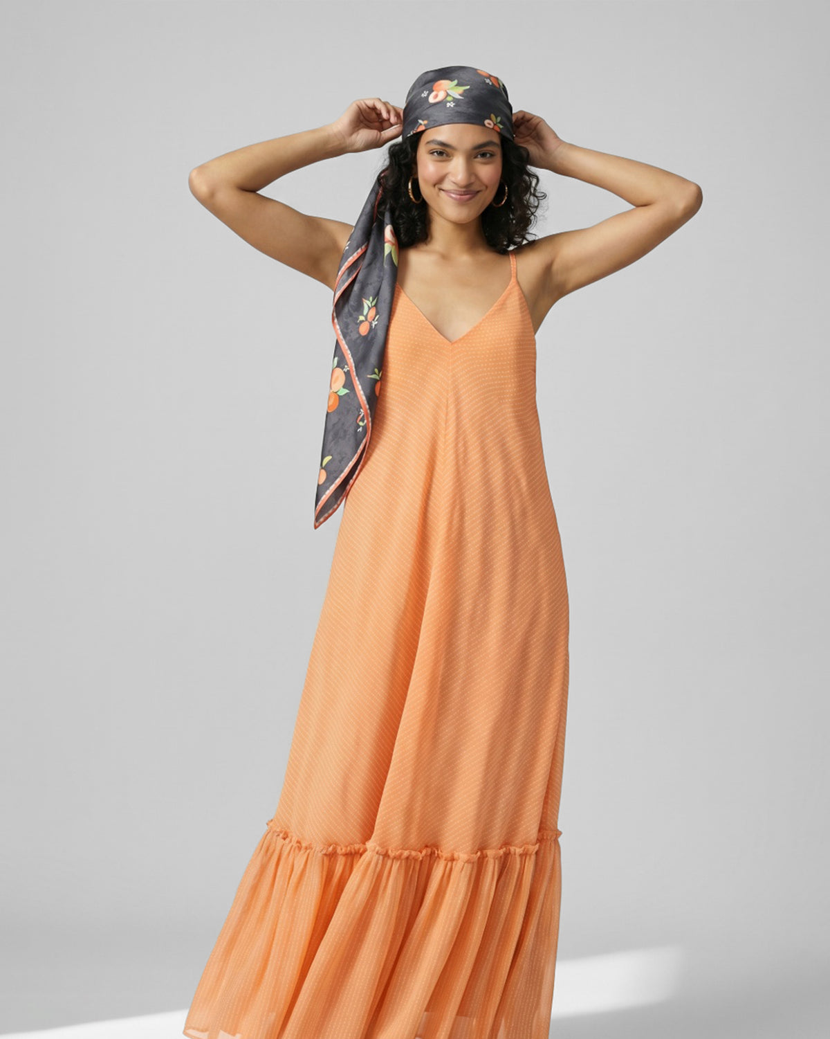 Person wearing a charcoal Apricot Scarf with peach print as a headscarf.