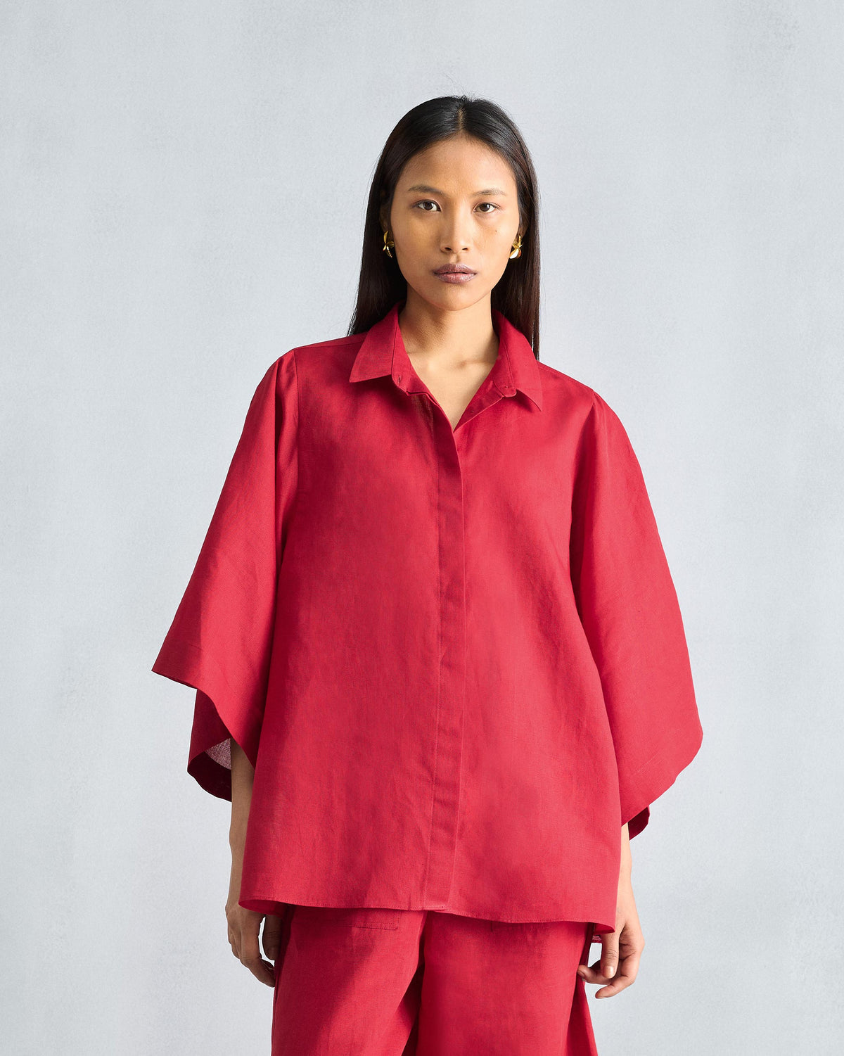 Person wearing the Drop Armhole Shirt Set in red with wide, flared sleeves.