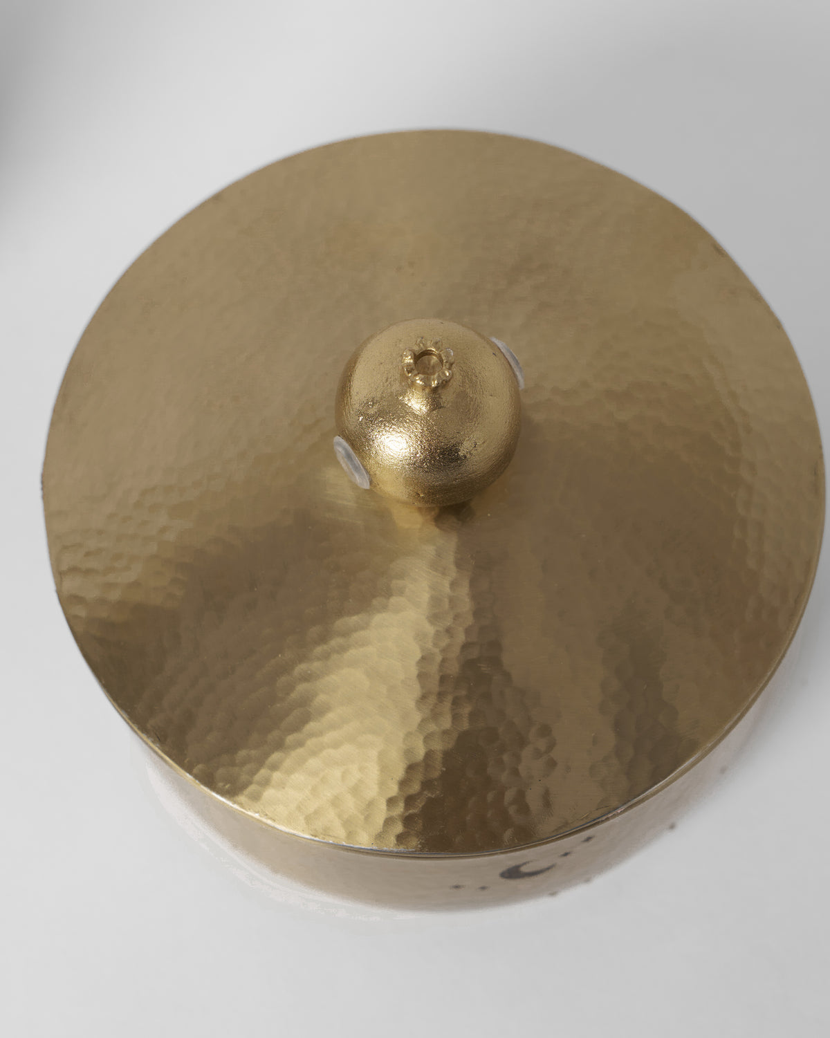 Top of a gold Chand tiffin box with a hammered lid and finial.