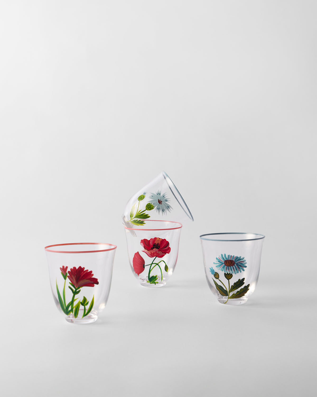 Group of four Rit tumblers with red and blue floral motifs, one tilted on another.