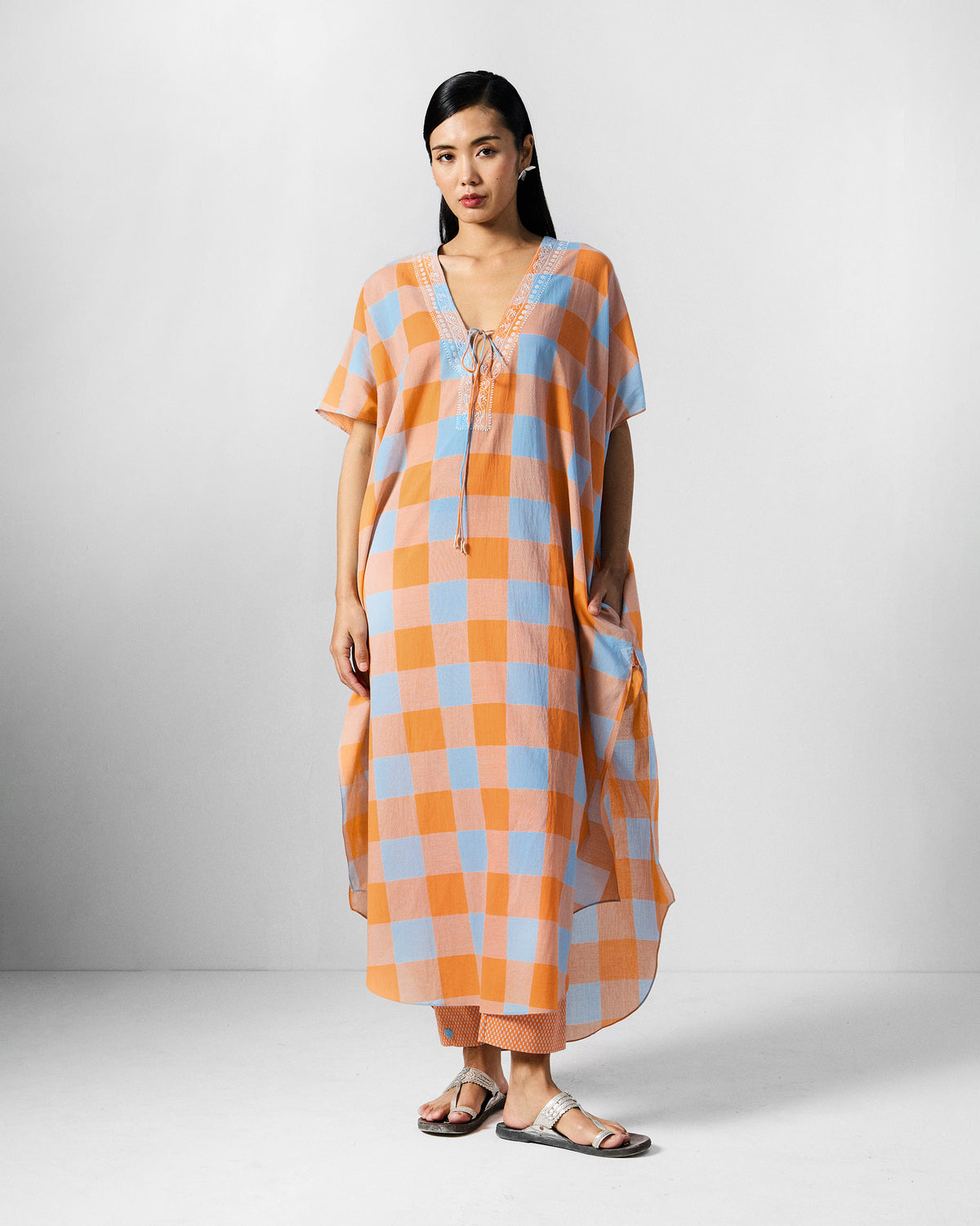 Person wearing an orange and blue check Vaya Kaftan Set with orange pants.