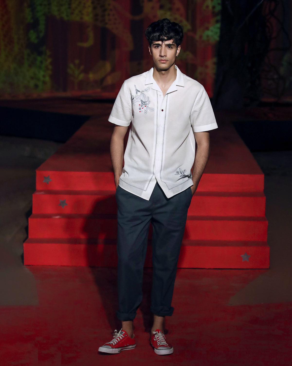 Person wearing a white Delta shirt with floral embroidery.