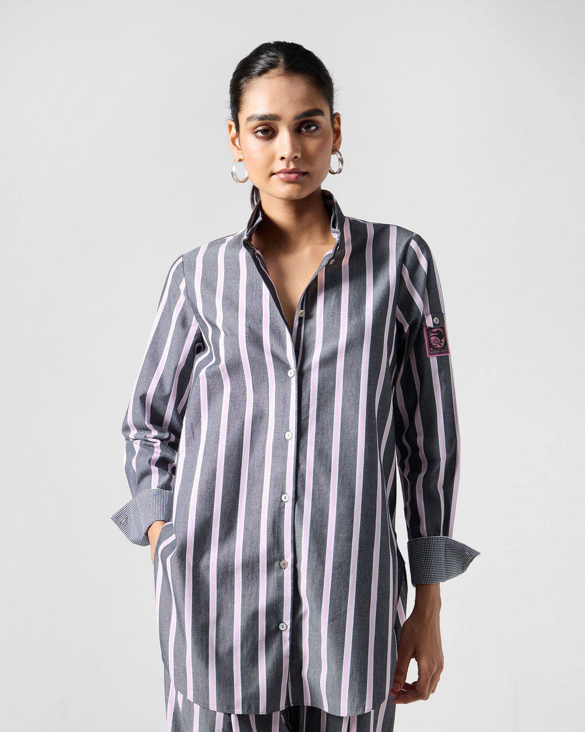 Person wearing a charcoal and pink striped Trench shirt with side pockets.