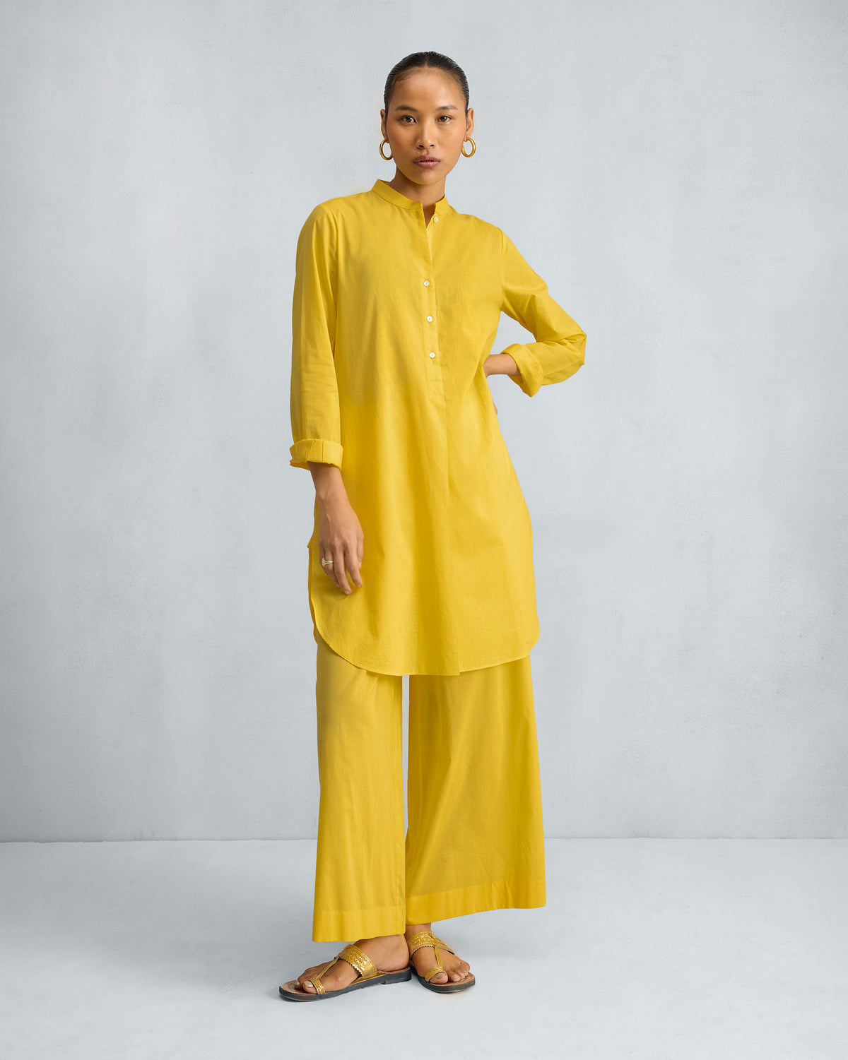 Person wearing a bright yellow mid-length kurta set with matching wide-leg pyjamas.
