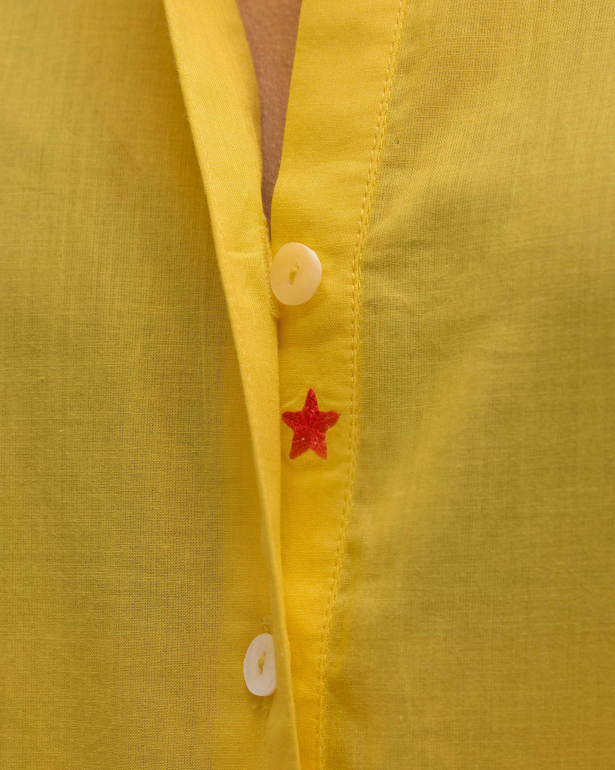 Close-up of the yellow kurta button placket with a small red embroidered star.